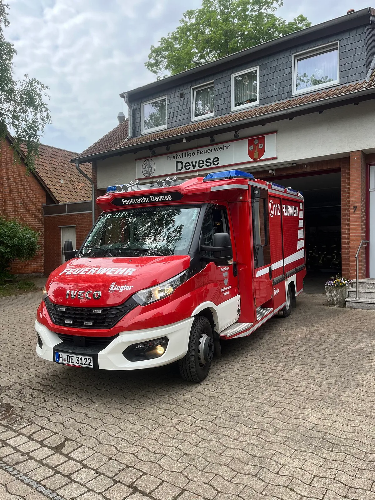 Mittleres Löschfahrzeug vor einem Feuerwehrgerätehaus