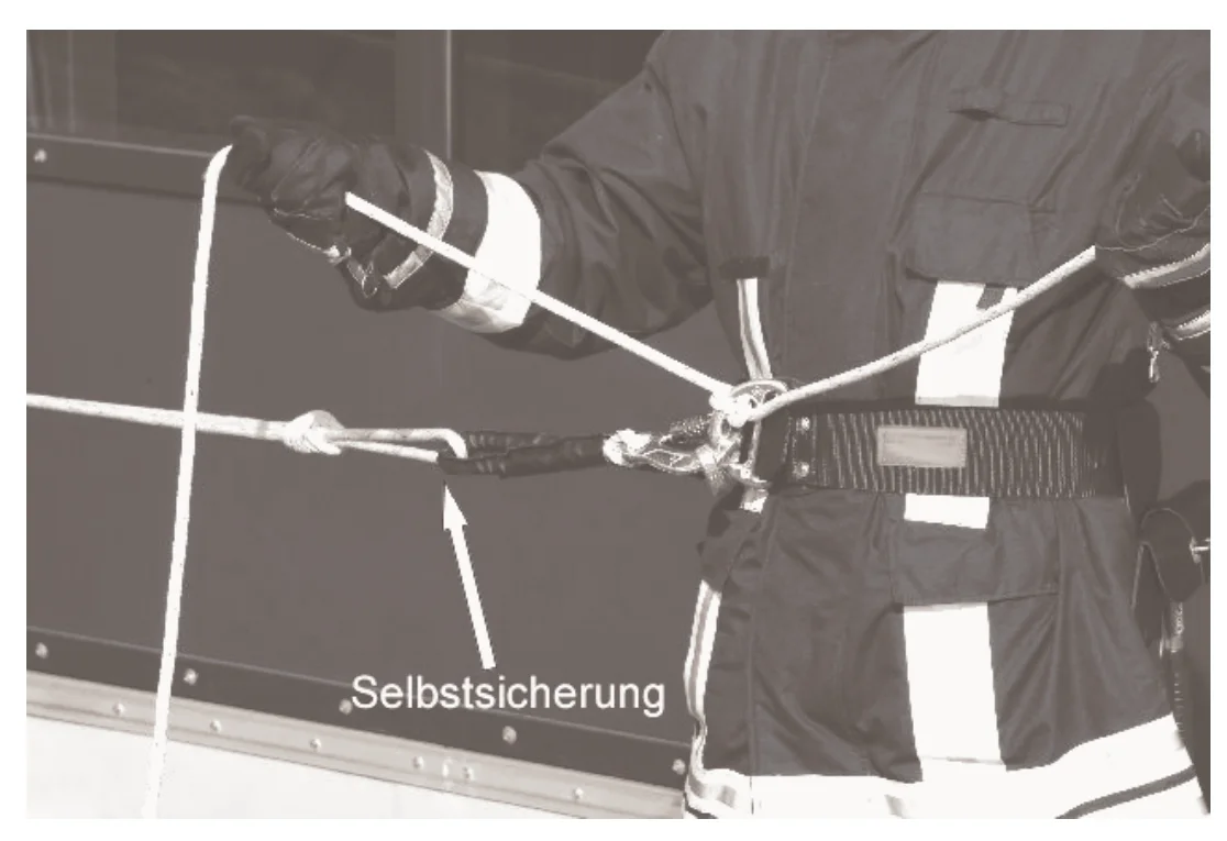 Haltender mit Halbmastwurf an der geschlossenen Halteöse; beschriftet: Selbstsicherung
